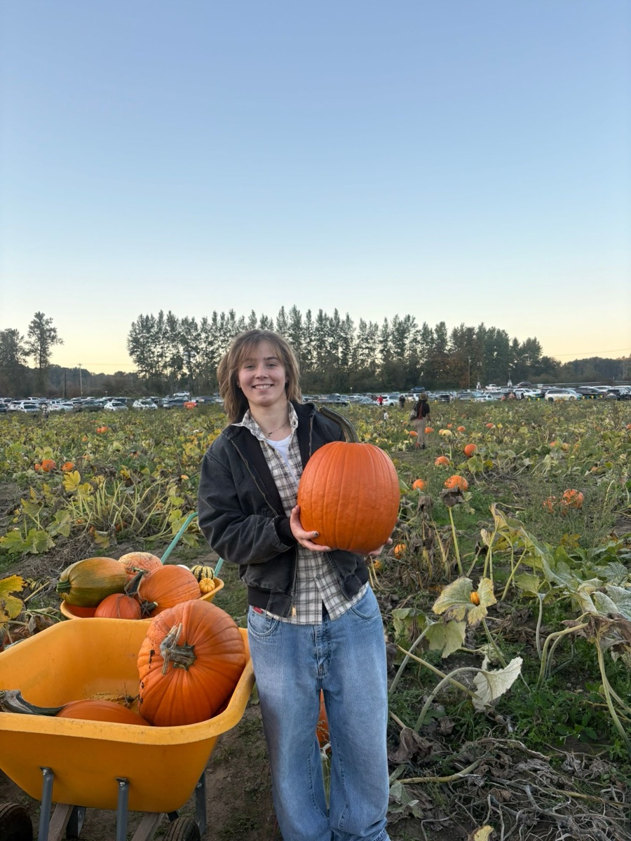 Alysa holding a large pumpkin in a pumpkin patch at sunset